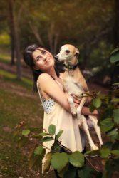 Girl with Italian greyhound in her arms in the park.