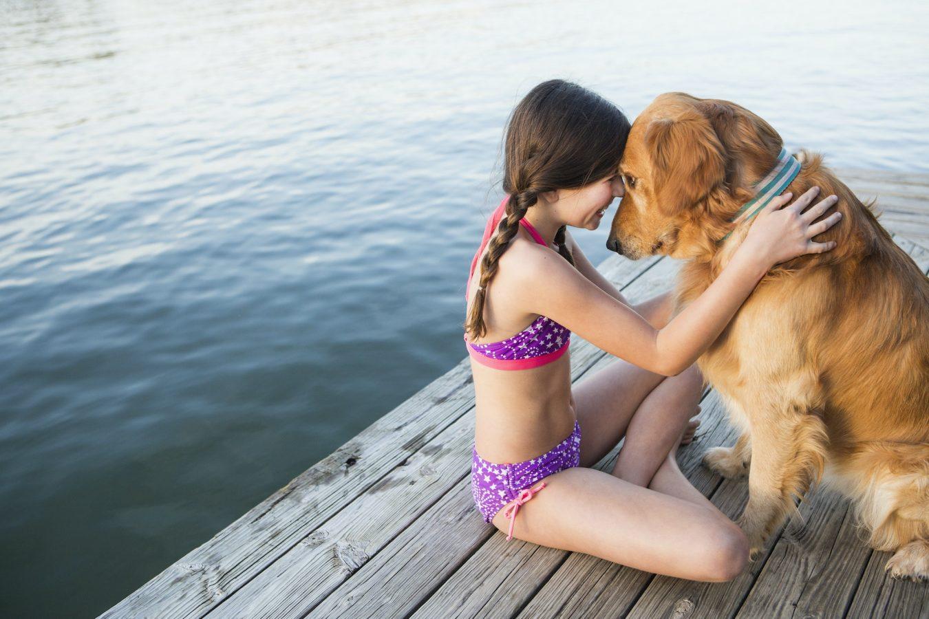 Golden Retrievers: The Best Dogs In The World? 2 A young girl and a golden retriever dog sitting on a jetty.